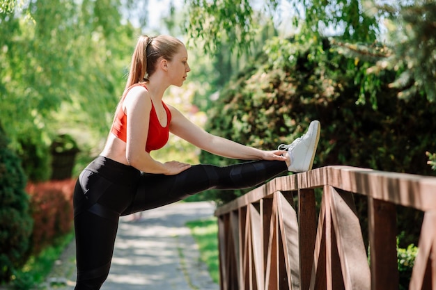 Sportowa blond kaukaska kobieta robi ćwiczenia rozciągające w parku