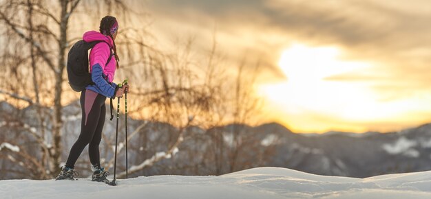 Sportowa Dziewczyna Ogląda Zachód Słońca Podczas Wędrówki W Rakietach śnieżnych