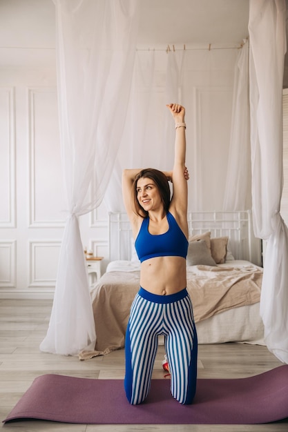 Sportowa dziewczyna robi ćwiczenia rozciągające rozgrzewkę rano w domu przy łóżku wysokiej jakości zdjęcie