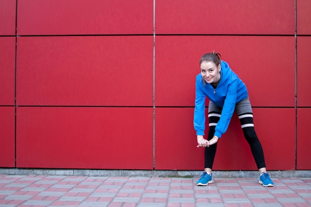 Sportowa dziewczyna trenuje na czerwonej ścianie na ulicy