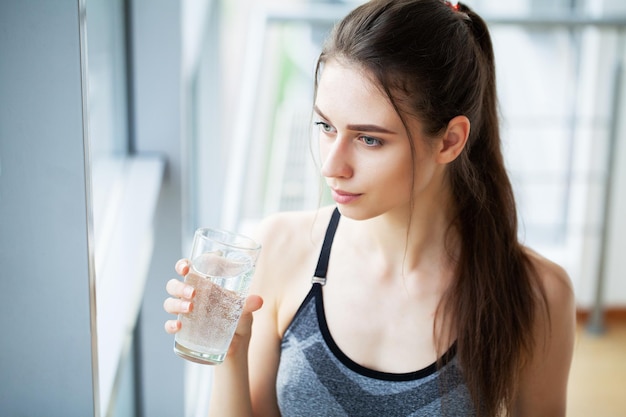 Sportowa kobieta pijąca wodę z butelki po treningu