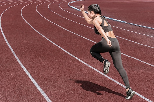 Sportowa Kobieta Prowadzi Zdrowe Mięśnie Ciała, Mocne, Wydajne I Potężne Na Tle Pola Do Biegania