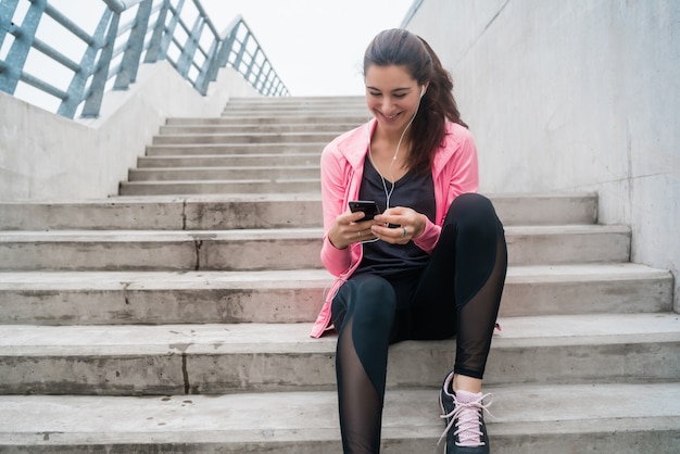 Sportowa kobieta używa jej telefon.