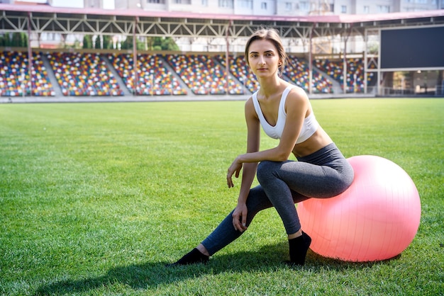 Zdjęcie sportowa kobieta z fitballem ćwicząca na świeżym powietrzu na zielonej trawie