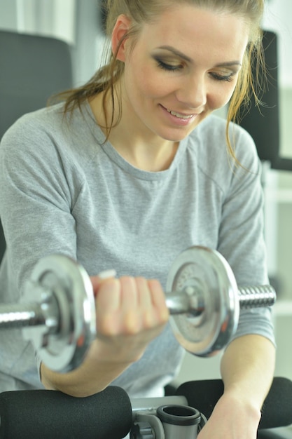 Sportowa młoda kobieta trenuje z hantlami w siłowni