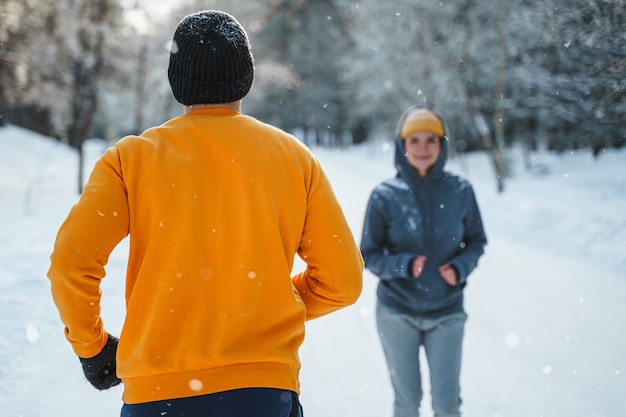 Sportowa para podczas zimowego joggingu w zaśnieżonym parku miejskim