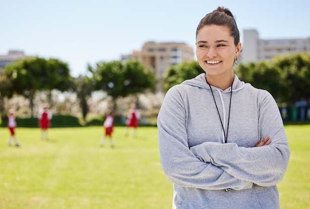 Sportowa piłka nożna i coaching z kobietą na boisku piłkarskim ze skrzyżowanymi rękami do treningu fitness lub przywództwa w pracy zespołowej Wsparcie motywacji i uśmiech z trenerem i sportowcem dla dzieci dla celów i zdrowia