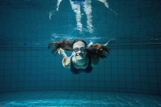 Sportowa pływaczka ono uśmiecha się przy kamerą podwodną