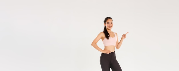 Sportowa siłownia i koncepcja zdrowego ciała na całej długości uśmiechniętej pięknej azjatyckiej sportsmenki w odzieży sportowej