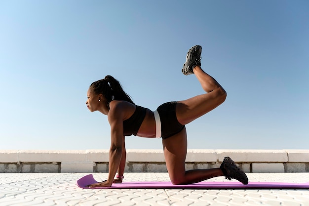 Sportowa wielorasowa kobieta fitness rozgrzewająca muskularne ciało do biegania na plaży