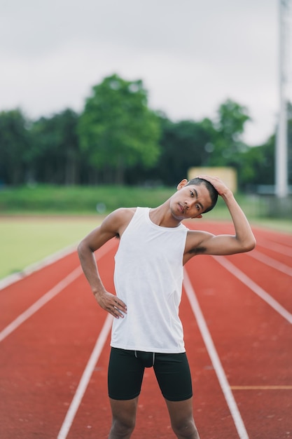 Sportowcy sport man biegacz ubrany w białą odzież sportową do rozciągania i rozgrzewki przed ćwiczeniem na bieżni na stadionie Koncepcja sportowa biegacza