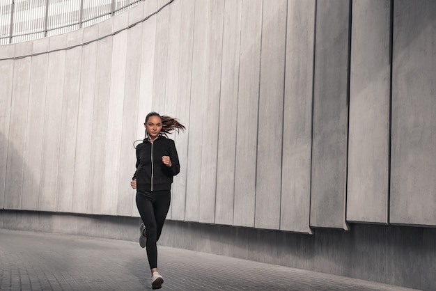 Sportowiec biegacz biegnie w pobliżu stadionu. Kobieta jogging koncepcja odnowy biologicznej treningu.