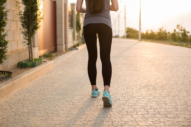 Sportowiec biegacz stopy biegają po drodze zbliżenie na butach kobieta fitness wschód jog trening wellness