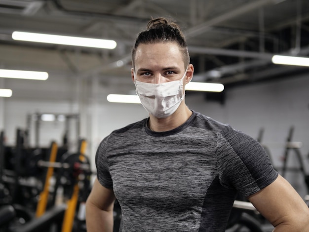 Sportowiec ćwiczący na siłowni podczas pandemii noszący maskę ochronną