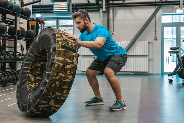 Sportowiec ćwiczący z kołem treningowym i wyglądający na zdeterminowanego