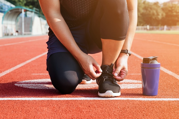 Sportowiec mężczyzna siedzi na sznurowadło na stadionie