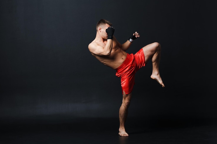 Zdjęcie sportowiec muay thai bokser postawa i kopnięcie kolanem na czarnym tle