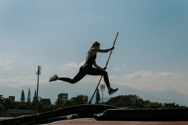 Zdjęcie sportowiec o wysokiej wydajności w bieganiu na torze lekkoatletycznym i skoku na słupie