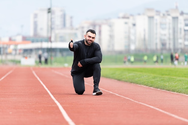 Sportowiec odpoczywa po bieganiu na zewnątrz pokazując kciuk w górę