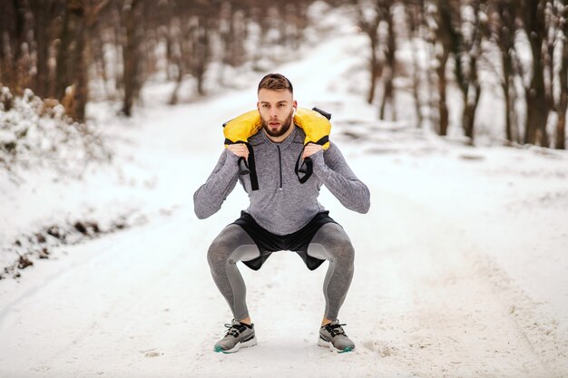 Sportowiec podnoszący ciężary w przyrodzie na śnieżną pogodę w przyrodzie.