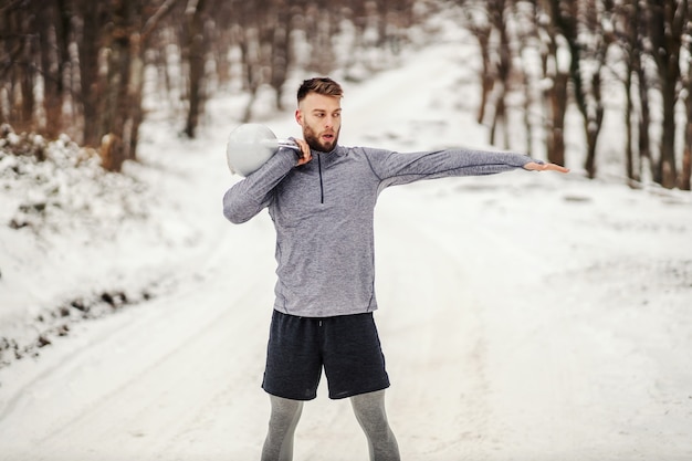 Sportowiec Podnoszący Kettlebell Stojąc Na Zaśnieżonej ścieżce W Lesie. Fitness Zimowy, Zdrowy Tryb życia, Kulturystyka