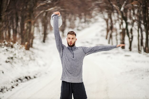 Sportowiec Podnoszący Kettlebell Stojąc Na Zaśnieżonej ścieżce W Lesie. Fitness Zimowy, Zdrowy Tryb życia, Kulturystyka