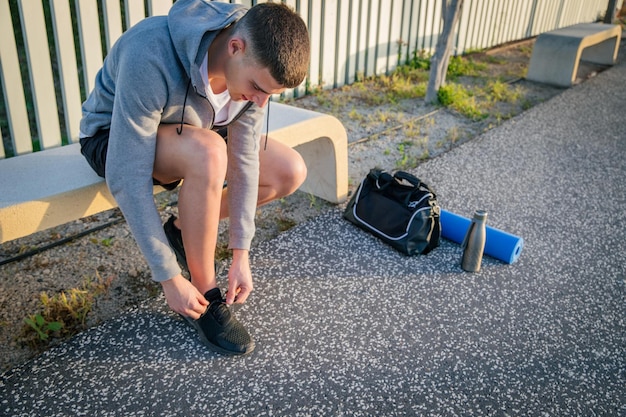 Sportowiec siedzący na ławce wiąże zdjęcie swoich butów z miejscem na kopię