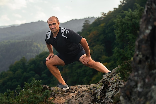 sportowiec uprawiający rozciąganie i ćwiczenie na zboczu wysokiej góry