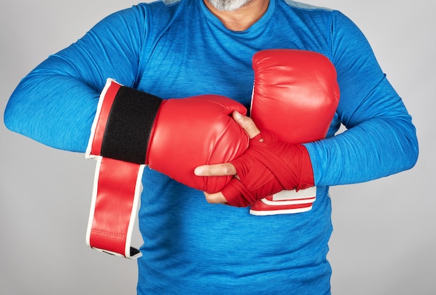 Sportowiec w niebieskich ubraniach, ręce są przewijane czerwonym bandażem