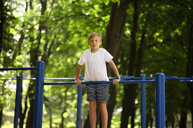 Sportowiec w parku podciągnął się na drążku i wisiał na rękach