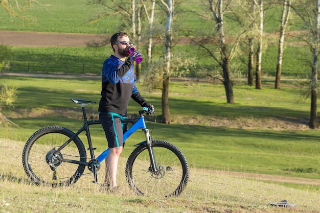 Sportowy brutalny brodaty facet na nowoczesnym rowerze górskim Rowerzysta w opuszczonym przez sól miejscu nad jeziorem