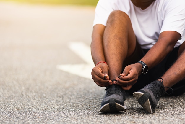 Sportowy czarny człowiek nosić zegarek siedzi siedzi on próbuje buty do biegania sznurowadło