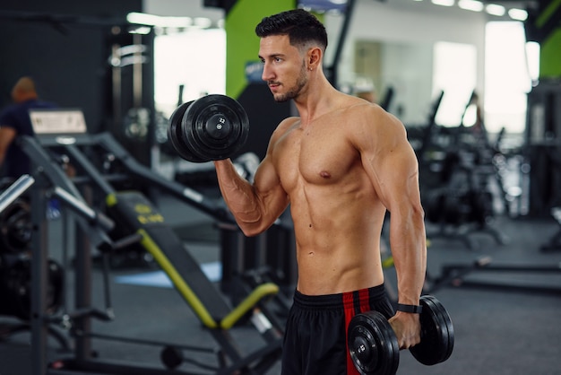 Sportowy Fitness Mężczyzna Robi ćwiczenia Na Biceps Przy Użyciu Hantli Na Stylowej Siłowni