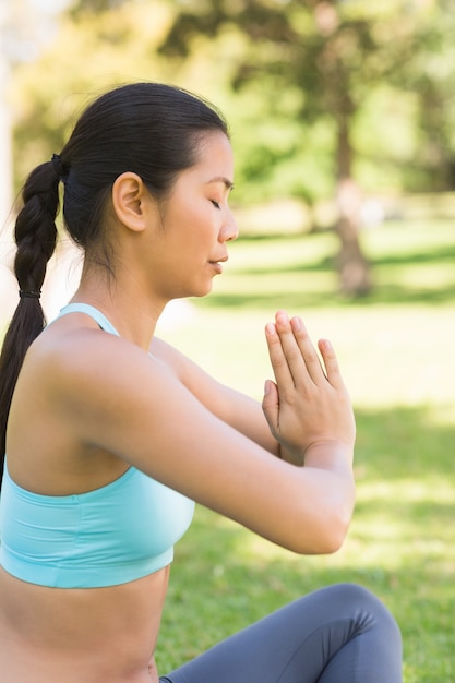 Sportowy kobieta w pozycji Namaste z zamkniętymi oczami w parku