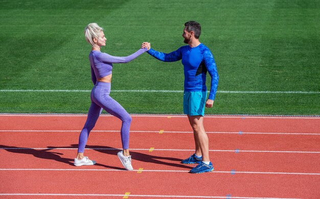 Zdjęcie sportowy mężczyzna i kobieta fitness partnerzy świętują zwycięstwo zespołu gestem uściśnięcia dłoni po ćwiczeniach lub rywalizacji w armwrestlingu na stadionie bieżnia arena sukces sportowy na świeżym powietrzu