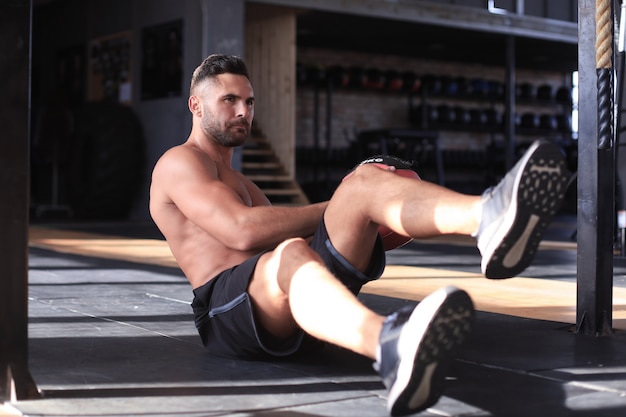 Sportowy mężczyzna rozciągający się i rozgrzewający wykonujący specjalne ćwiczenia na mięśnie przed treningiem swojego ciała.