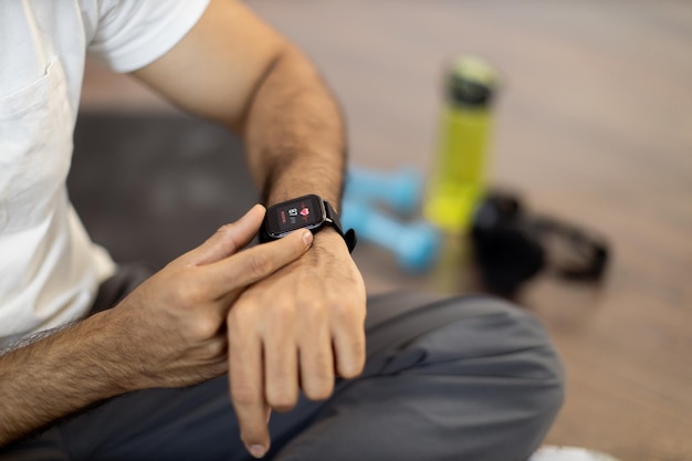 Sportowy mężczyzna sprawdza puls na smartwatchu po treningu w środku