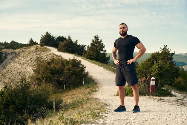 Sportowy mężczyzna stojący na wzgórzu na wsi