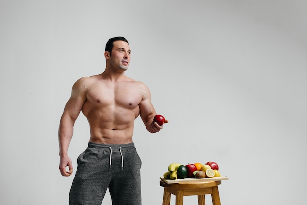 Sportowy seksowny facet pozowanie z jasnych owoców. Dieta. Zdrowa dieta