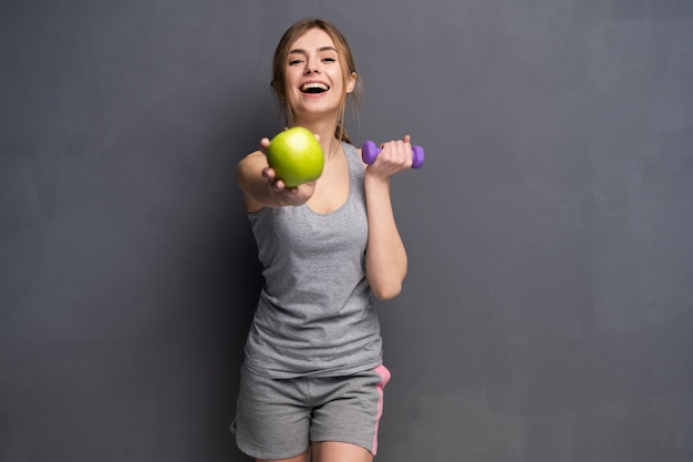 Sportowy Sprawny Kobieta Trzymając Hantle Wagi W Jednym I Jabłko Owoc W Drugiej Ręce