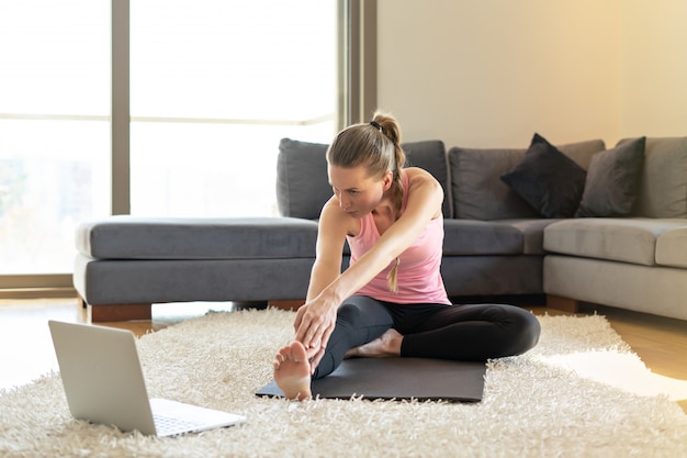 Sportowy trening jogi fitness online. młoda kobieta i robienie ćwiczeń na matę do jogi