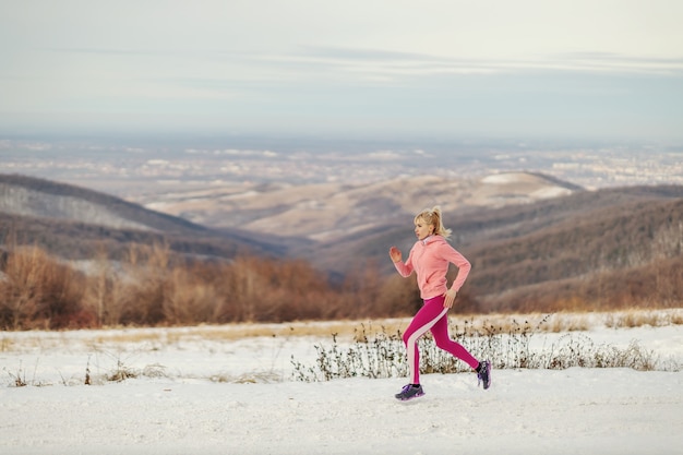 Sportsmenka w kształcie działa w przyrodzie w mroźny zimowy dzień. Zdrowe nawyki, fitness zimowy, ćwiczenia cardio