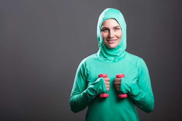 Sportwoman w zielonej odzieży sportowej na szarym tle