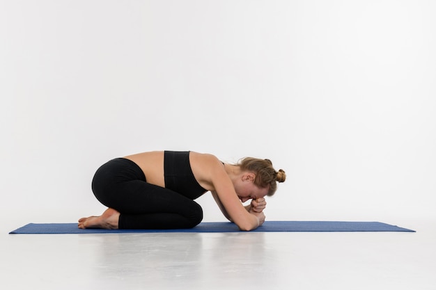 Sporty atrakcyjna młoda kobieta robi joga praktyce na białym tle. Pozycja dziecka, Balasana.