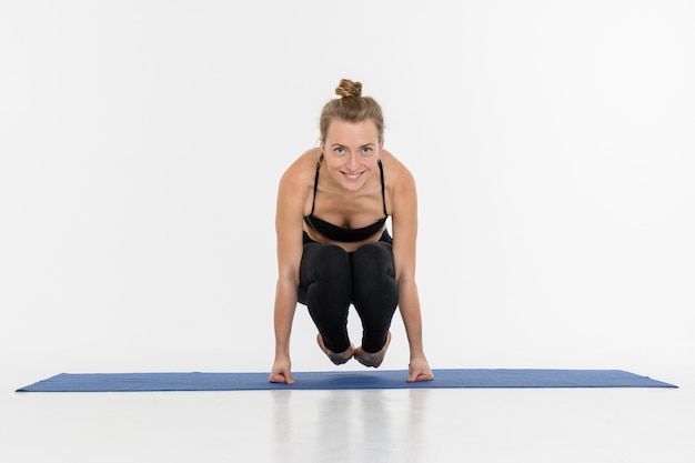 Sporty atrakcyjna młoda kobieta robi joga praktyce na białym tle. Wrona - Bakasana.