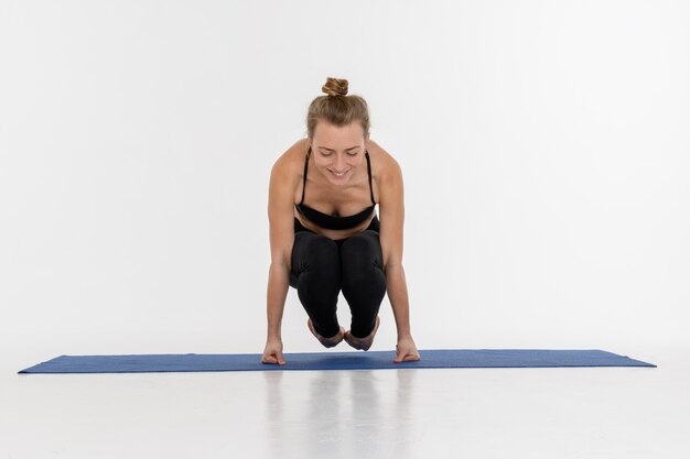 Sporty atrakcyjna młoda kobieta robi joga praktyce na białym tle. Wrona - Bakasana.