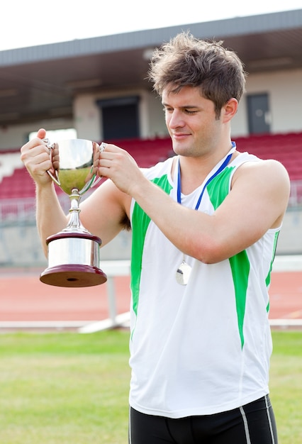 Sporty mężczyzna trzyma filiżankę i medal