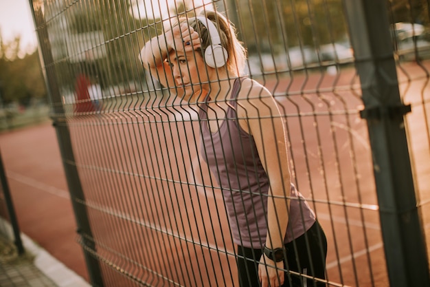 Sporty młoda kobieta odpoczywa metalem ogradza