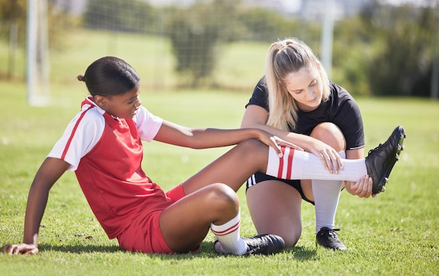 Sporty piłkarskie i kontuzje zawodniczki cierpiącej na ból nogi lub kostki na boisku Bolesny ból i dyskomfort kobiety podczas sprawdzania jej bólu przez trenera sportowego na boisku