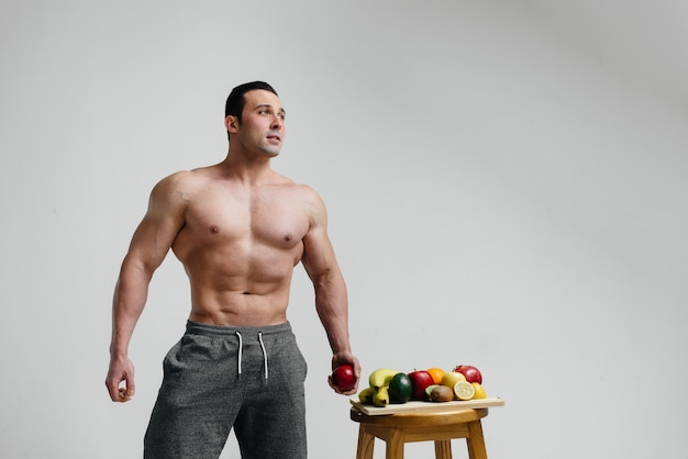 Sporty seksowny facet pozuje na białym tle z jaskrawymi owoc. Dieta. Zdrowa dieta.